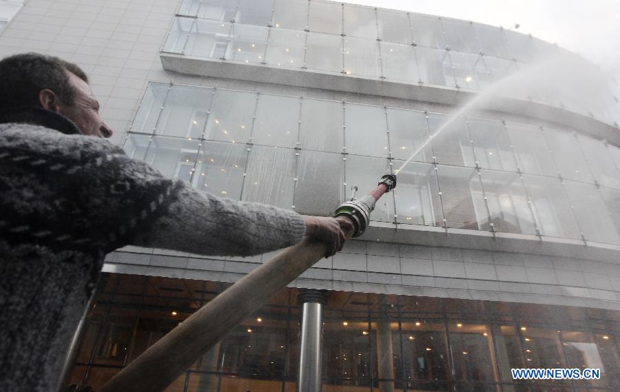 A dairy farmer sprays milk to European Parliament building during a protest against EU agricultural policies at the Place du Luxembourg in Brussels, capital of Belgium, on Nov. 26, 2012. Dairy farmers from all over Europe demonstrated today with about 1,000 tractors at the European Parliament in Brussels to protest against falling milk prices caused by overproduction in the continent. (Xinhua/Zhou Lei) 