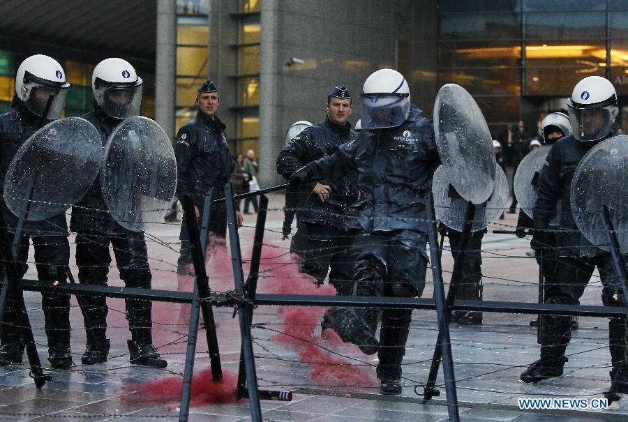 A policeman kicks away the smoke bomb thrown by dairy farmers during a protest against EU agricultural policies at the Place du Luxembourg, outside the European Parliament in Brussels, capital of Belgium, on Nov. 26, 2012. Dairy farmers from all over Europe demonstrated today with about 1,000 tractors at the European Parliament in Brussels to protest against falling milk prices caused by overproduction in the continent. (Xinhua/Zhou Lei) 