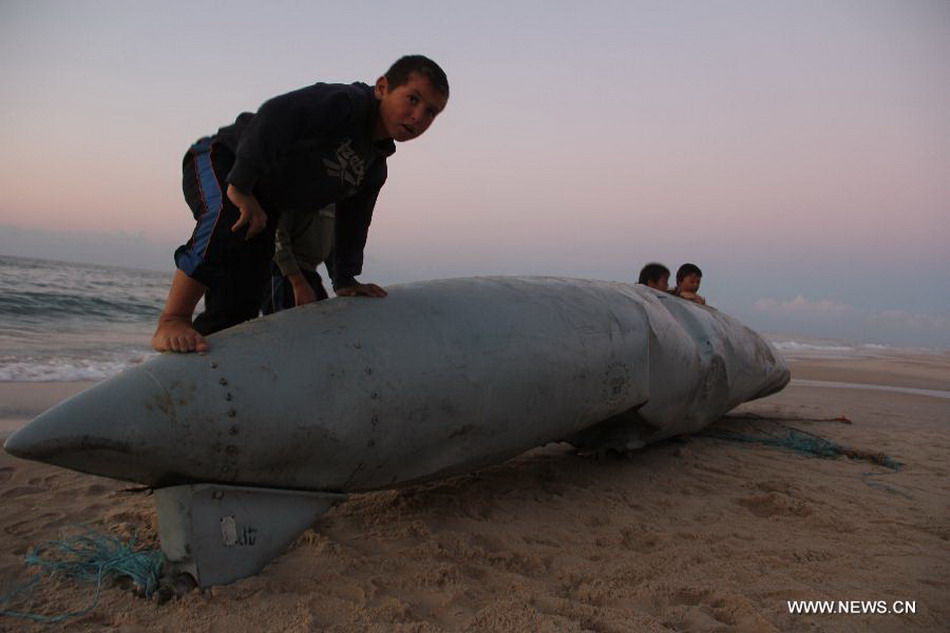 Palestinians children play around what appears to be a part of an aircraft, which was washed ashore near Rafah, in the southern Gaza Strip, on Nov. 26, 2012. Hamas media outlets claimed that a part of an Israeli F-16 was brought down by militants and washed up on shore. (Xinhua/Khaled Omar)  