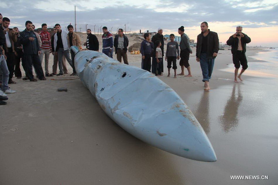 Palestinians gather around what appears to be a part of an aircraft, which was washed ashore near Rafah, in the southern Gaza Strip, on Nov. 26, 2012. Hamas media outlets claimed that a part of an Israeli F-16 was brought down by militants and washed up on shore. (Xinhua/Khaled Omar)  
