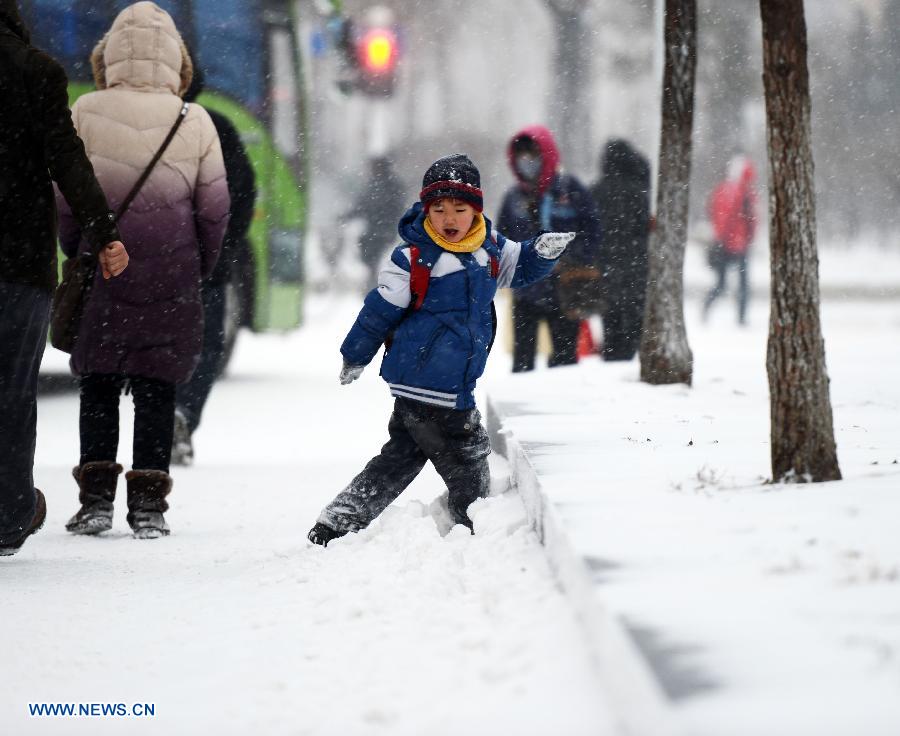A primary school boy plays with snow on his way to school in Harbin, capital of northeast China's Heilongjiang Province, Nov. 28, 2012. Cold air front moving eastward will sweep China's northern regions during the next few days, bringing strong winds and big temperature drops, the National Meteorological Center (NMC) forecast on Wednesday. (Xinhua/Wang Kai) 