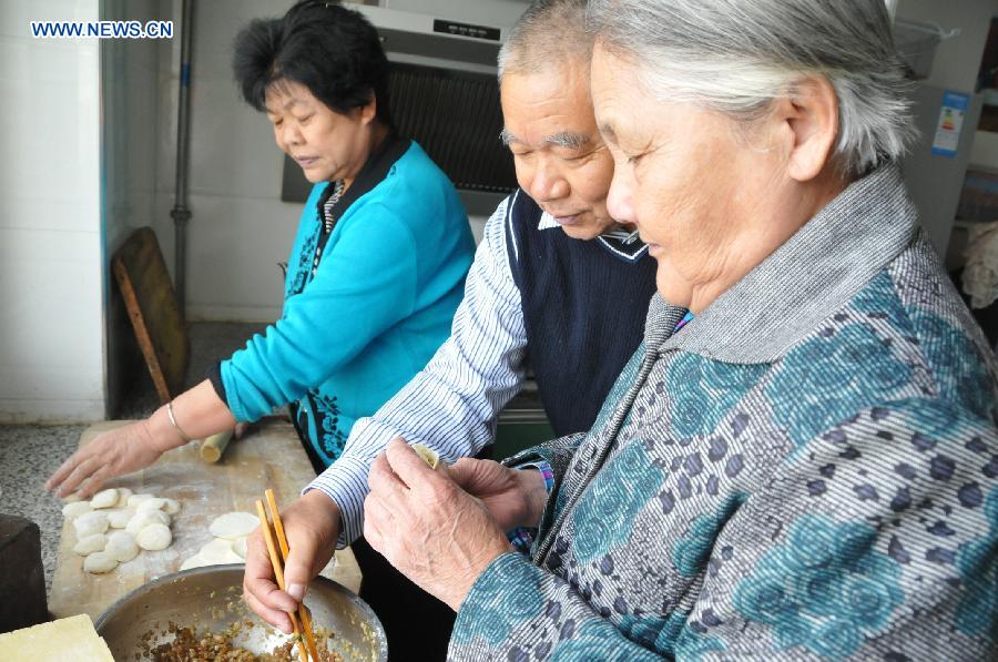 Zhu Qingzhang makes dumplings with his adoptive mother Han Fuzhen and his wife at home in Baotou, north China's Inner Mongolia Autonomous Region, Nov. 27, 2012. An accident left Zhu Qingzhang's adoptive mother Han Fuzhen in a vegetative state in 1975. Since then, Zhu has been looking after his adoptive mother while doing his own job. And all his love for his adoptive mother paid off when Han finally woke up 31 years later. Under the care of 62-year-old Zhu, 86-year-old Han now lives a happy and healthy life. (Xinhua/Liu Yide) 