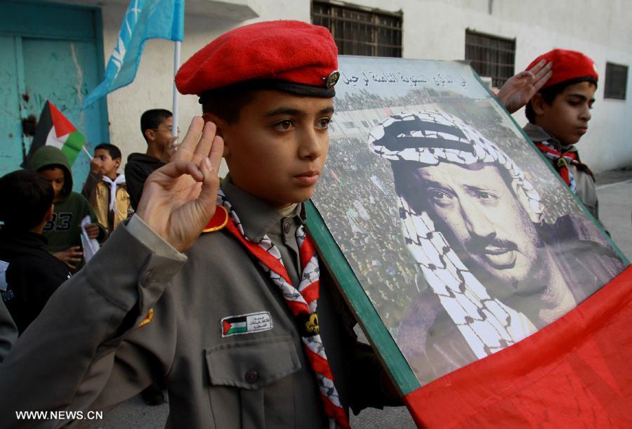 Palestinian students hold a poster of the late Palestinian leader Yasser Arafat during a memorial ceremony at a school in the West Bank city of Nablus, on Nov. 27, 2012. Palestinian engineers dug up the tomb of Arafat to take samples from his remains for poison tests at dawn Tuesday, sources said. (Xinhua/Nidal Eshtayeh)