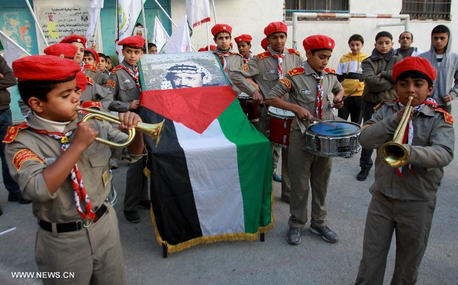 Palestinian students hold a poster of the late Palestinian leader Yasser Arafat during a memorial ceremony at a school in the West Bank city of Nablus, on Nov. 27, 2012. Palestinian engineers dug up the tomb of Arafat to take samples from his remains for poison tests at dawn Tuesday, sources said. (Xinhua/Nidal Eshtayeh)