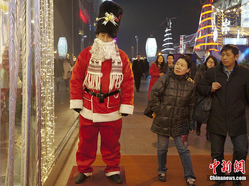 A security staff of Xidan shopping mall dressed up as "Santa Claus" at the entrance has attracted a lot of attention from the public in Beijing, Dec. 10, 2011. (Chinanews.com/Liu Guanguan)