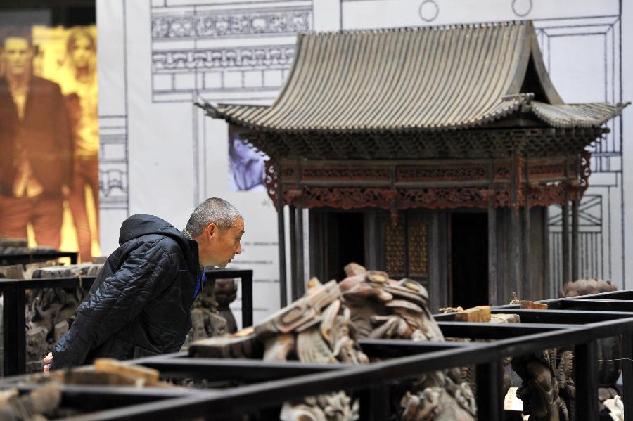 A man looks at items displayed at an exhibition of ancient Chinese architectural woodcarving components in Jinan, capital of east China's Shandong Province, Nov. 29, 2012.  (Xinhua/Guo Xulei)