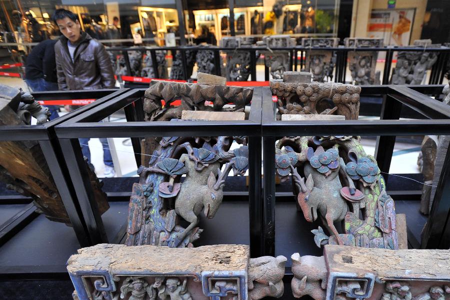 A man looks at items displayed at an exhibition of ancient Chinese architectural woodcarving components in Jinan, capital of east China's Shandong Province, Nov. 29, 2012. (Xinhua/Guo Xulei)
