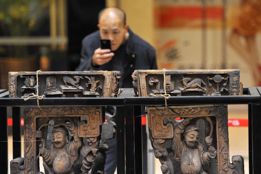 A man takes pictures of items displayed at an exhibition of ancient Chinese architectural woodcarving components in Jinan, capital of east China's Shandong Province, Nov. 29, 2012. (Xinhua/Guo Xulei)