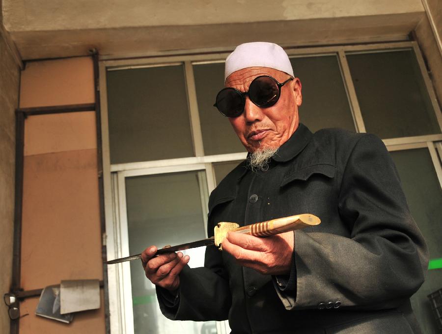 Ma Dexiang, a veteran Bao'an broadsword maker, checks the quality of a newly forged broadsword in Jishishan County, northwest China's Gansu Province, Nov. 29, 2012. (Xinhua/Huang Wenxin) 