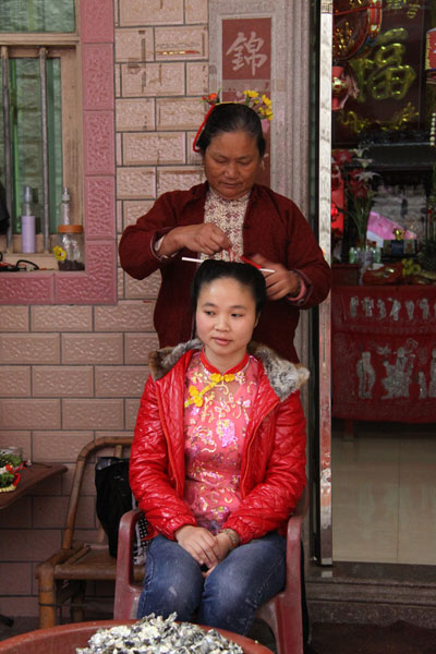 In Xunpu Village in Quanzhou City, the local women are famous for their custom of putting fresh flowers in their hair. This seemingly odd hairdo is unique and attracts the curiosity of tourists. One or two circles of flowers of different colors and types are put in the hair. (CRIENGLISH.com/Luo Chun)