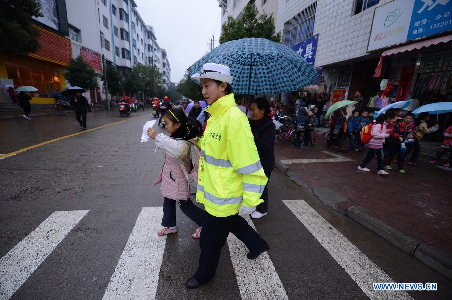 A traffic policewoman escorts a schoolgirl crossing the road in Wan'an County, east China's Jiangxi Province, Nov. 28, 2012. 