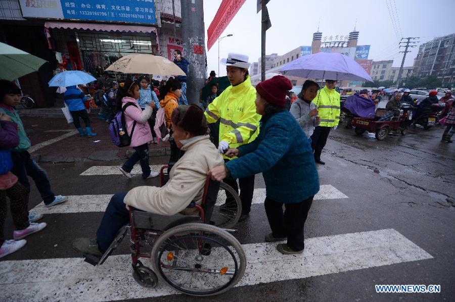 A traffic policewoman escorts a disabled person crossing the road in Wan'an County, east China's Jiangxi Province, Nov. 28, 2012. 