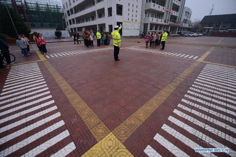 Police officers show the pupils how to direct the traffic at the Wan'an Experimental Primary School in Wan'an County, east China's Jiangxi Province, Nov. 28, 2012. 
