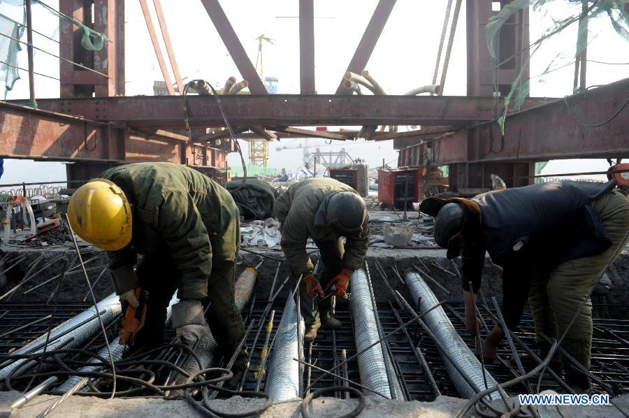 Laborers work on the Bapanxia Yellow River bridge of the second line of Lanxin (Lanzhou-Xinjiang) Railway in Yongqing, northwest China's Gansu Province, Nov. 26, 2012.