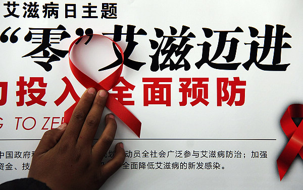 Students from Weiming middle school sign their names on a banner with red ribbons in Tancheng county, East China's Shandong Province on Nov 29, 2012. (Xinhua)