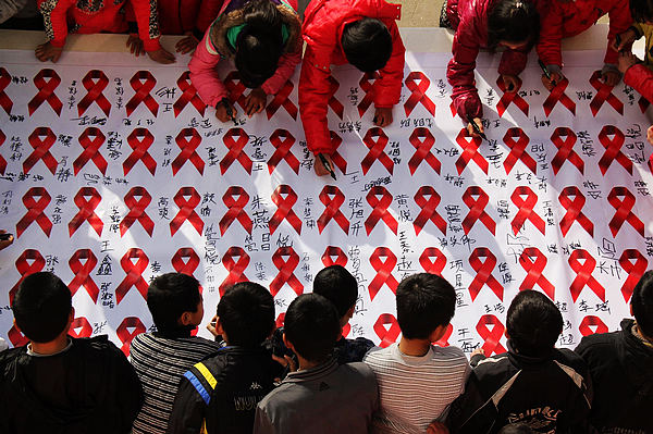 Students from Weiming middle school sign their names on a propaganda banner with red ribbons in Tancheng county, East China's Shandong province on Nov 29, 2012. (Xinhua)