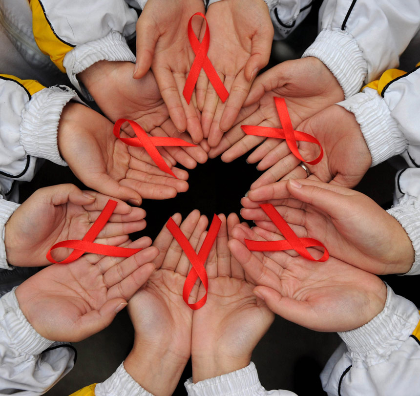 Volunteers from Chongqing show red ribbons on Nov. 30, 2012. The World AIDS Day falls on Dec. 1 and is marked all over the country. (Xinhua)