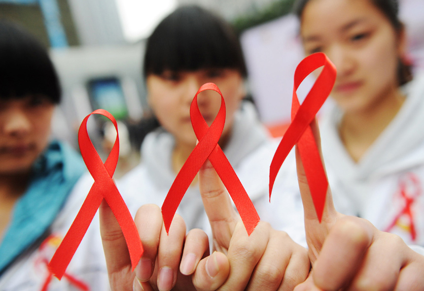 Volunteers from Chongqing show red ribbons on Nov. 30, 2012. The World AIDS Day falls on Dec. 1 and is marked across China. (Xinhua)