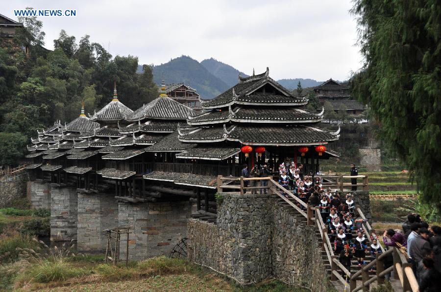 People of the Dong ethnic group walk through the Chengyang Fengyu Bridge in Sanjiang Dong Autonomous County, southwest China's Guangxi Zhuang Autonomous Region, Dec. 1, 2012. A celebration ceremony was held on Saturday to mark the 100th anniversary of the completion of Chengyang Fengshui Bridge. (Xinhua/Lai Liusheng) 