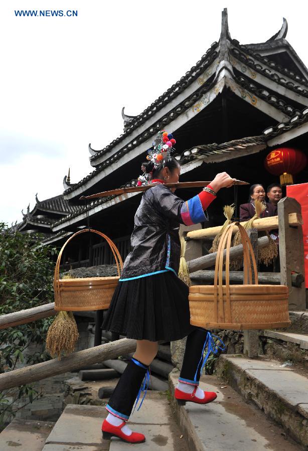 A woman of the Dong ethnic group carries food walking by the Chengyang Fengyu Bridge in Sanjiang Dong Autonomous County, south China's Guangxi Zhuang Autonomous Region, Dec. 1, 2012. A celebration ceremony was held on Saturday to mark the 100th anniversary of the completion of Chengyang Fengshui Bridge. (Xinhua/Lai Liusheng)  