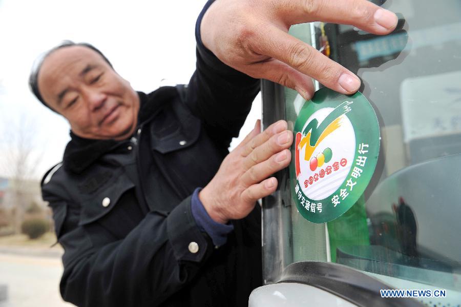A driver sticks a safety sign on his vehicle to mark the country's first national day for road safety in Yinchuan, capital of northwest China's Ningxia Hui Autonomous Region, Dec. 2, 2012. (Xinhua/Peng Zhaozhi)