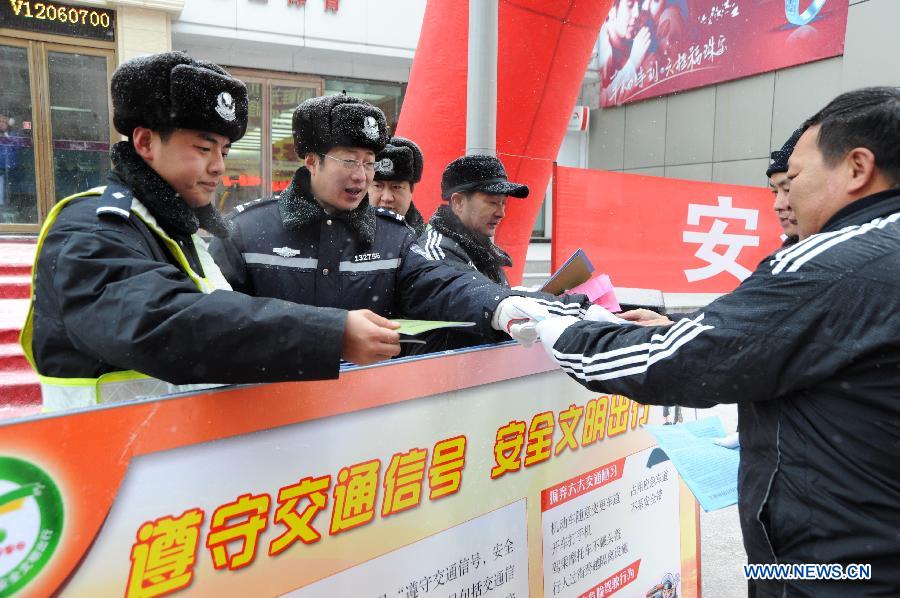 Traffic policemen distribute reading materials to introduce traffic safety knowledge during an event to mark the country's first national day for road safety in Heihe, northeast China's Heilongjiang Province, Dec. 2, 2012. (Xinhua/Qiu Qilong)