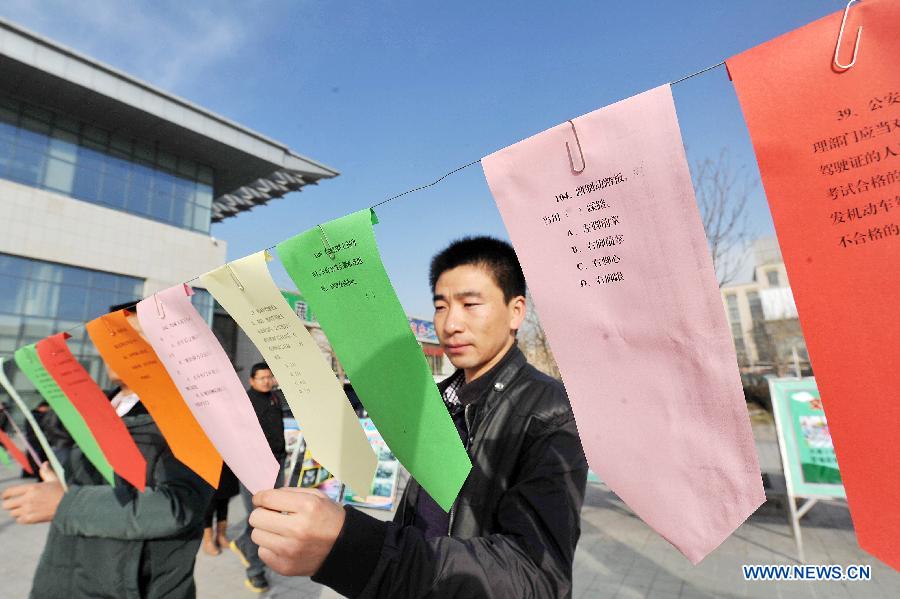 Citizens read questions during a guessing game on traffic safety knowledge to mark the country's first national day for road safety in Yinchuan, capital of northwest China's Ningxia Hui Autonomous Region, Dec. 2, 2012. (Xinhua/Peng Zhaozhi)