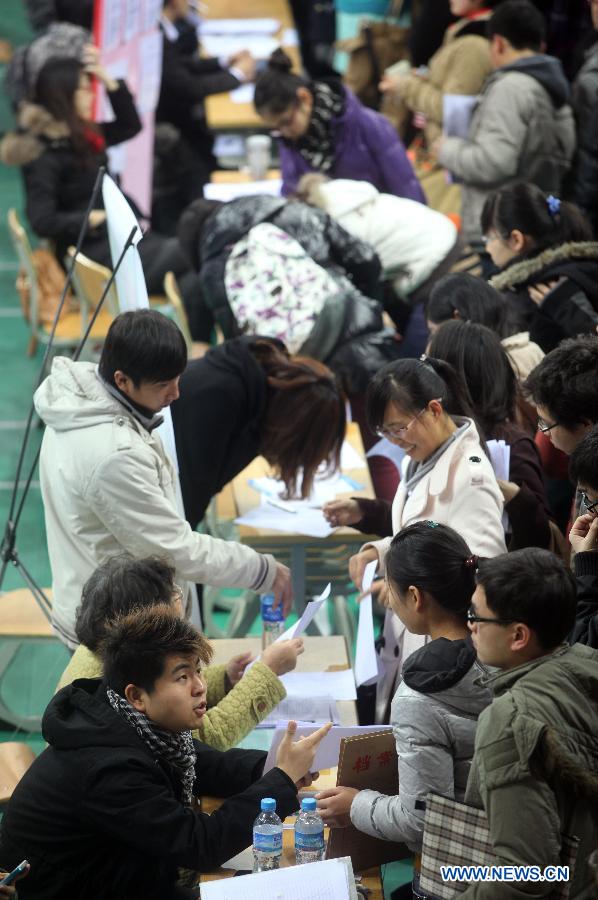 Students communicate with recruiters at a job fair in Tianjin Normal University in north China's Tianjin Municipality, Dec. 2, 2012. Tianjin Normal University held a job fair for its fresh graduates in 2013 on Sunday, which attracted over 200 enterprises. (Xinhua/Liu Dongyue)
