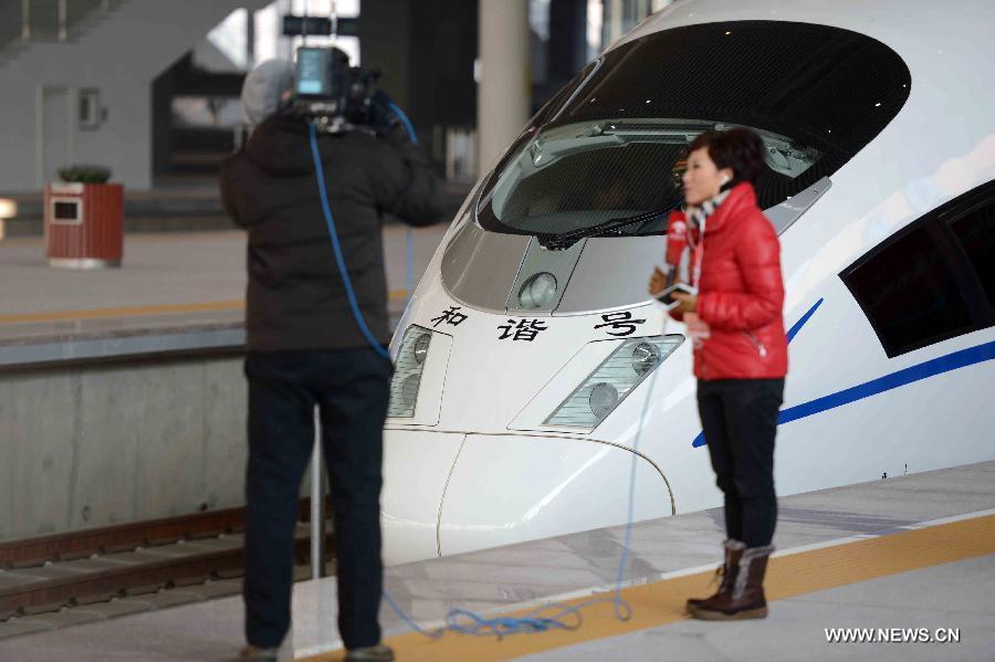 Reporters work in front of a high-speed train at the Harbin West Railway Station in Harbin, capital of northeast China's Heilongjiang Province, Dec. 1, 2012. The world's first high-speed railway in areas with extremely low temperature, which runs through three provinces in northeastern China, started operation on Saturday. The railway links Harbin, capital of Heilongjiang Province, and Dalian, a port city in Liaoning Province. (Xinhua/Wang Kai)