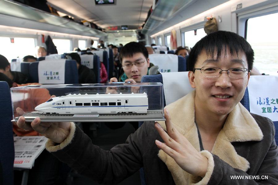 A passenger shows a model of a high-speed train he bought on the D501 high-speed train from Dalian North Railway Station to Harbin West Railway Station, Dec. 1, 2012. The world's first high-speed railway in areas with extremely low temperature, which runs through Liaoning, Jilin and Heilongjiang provinces in northeastern China, started operation on Saturday. The railway links Harbin, capital of Heilongjiang , and Dalian, a port city in Liaoning. (Xinhua/Zhang Chunlei)