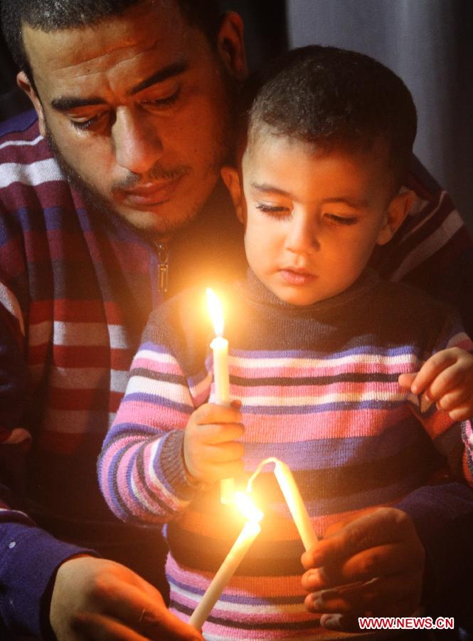 A Palestinian man and his kid light candles around the destroying house of Al-Dalou family in Gaza City on Dec. 1, 2012. An Israeli bomb fell upon Al-Dalou family's two-storey house in Gaza City's residential al-Nasser neighborhood on Nov.18, killing 11, including four children and a woman as old as 81. It was one of the deadliest events in the latest conflict between Israel and Gaza militants. (Xinhua/Yasser Qudih)