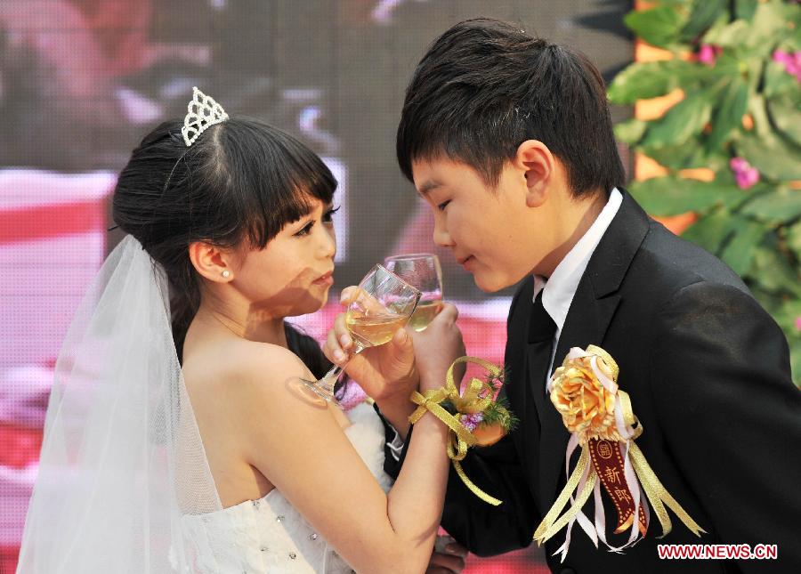 A couple drink cross-cupped wine during a group wedding in Beijing, capital of China, Dec. 1, 2012. Seven couples who are about 126-centimeter-tall from a Beijing shadow play troupe attended the group wedding on Saturday. (Xinhua/Li Wen) 