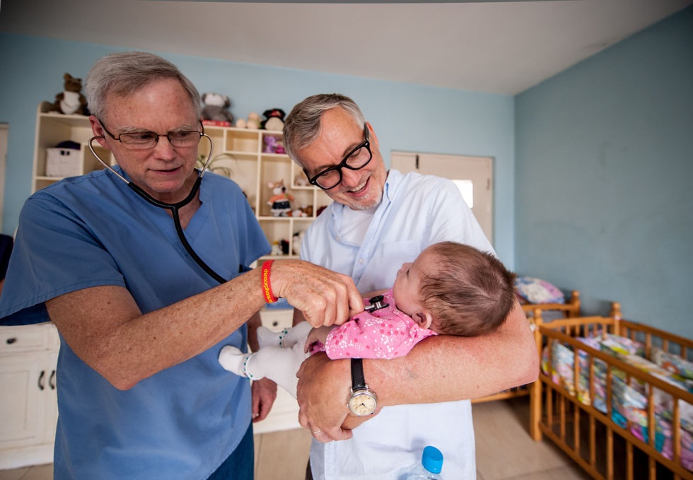 Tim Baker (R) holds a a child who suffers from heart conditions for a medical check-up by Doctor Moody at the Shepherd's Field in Tianjin, north China, May 29, 2012.(Xinhua/Zhang Chaoqun)