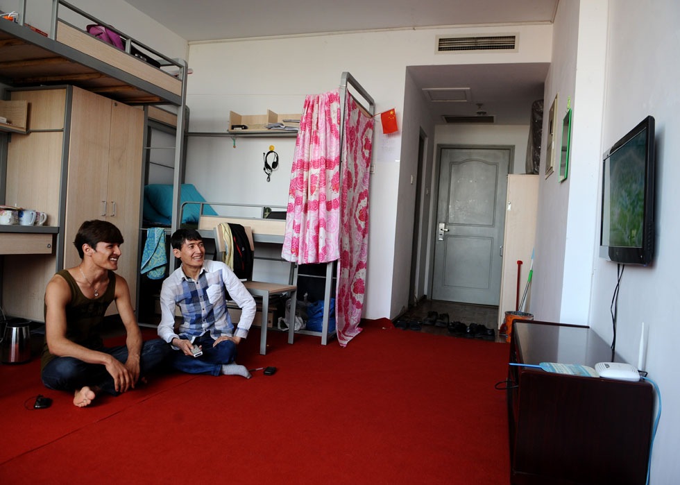 Salman Raha (R) and his roommate watch TV program in their dormitory at Taiyuan University of Technology in Taiyuan, capital of north China's Shanxi Province, June 14, 2012. 