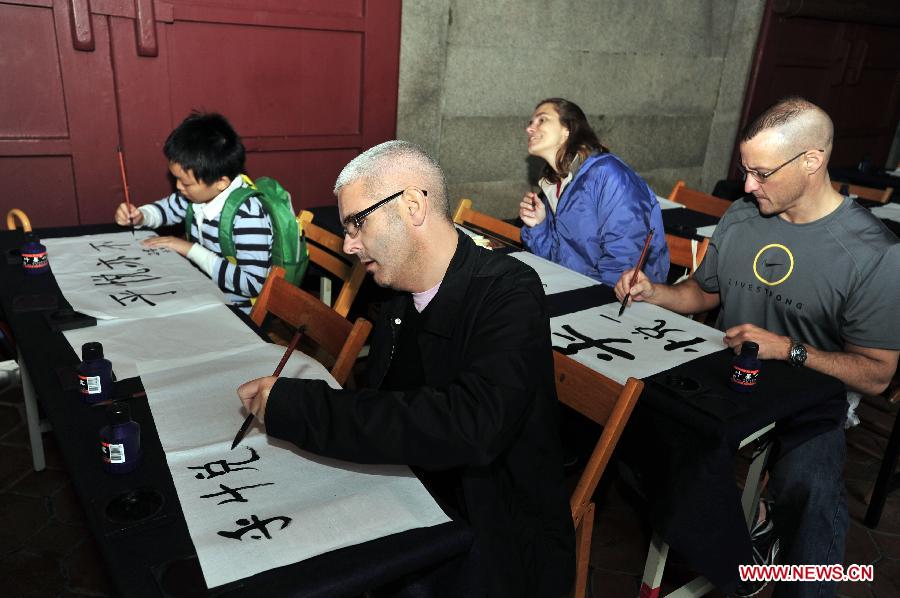 British tourists experience writing Chinese calligraphy during an activity at Taipei Confucius Temple in Taipei, southeast China's Taiwan Province, Dec. 2, 2012. (Xinhua/Wu Ching-teng)