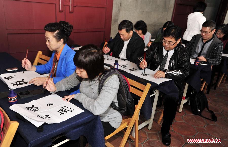 Members of a Chinese classics education delegation from China's capital Beijing experience writing calligraphy during an activity at Taipei Confucius Temple in Taipei, southeast China's Taiwan Province, Dec. 2,2012. (Xinhua/Wu Ching-teng)