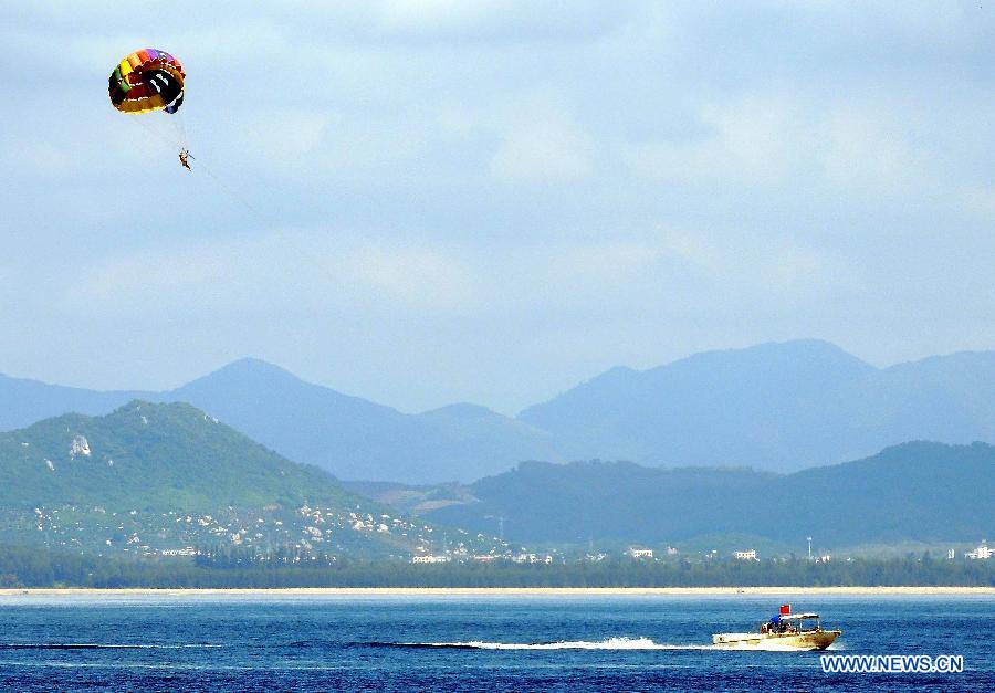 A tourist enjoys paraglider near Wuzhizhou Island, a scenic spot in Sanya, south China's Hainan Province, Dec. 1, 2012. Sanya has always been a winter tourism preferrence thanks to its tropical climate. (Xinhua/Wang Song) 