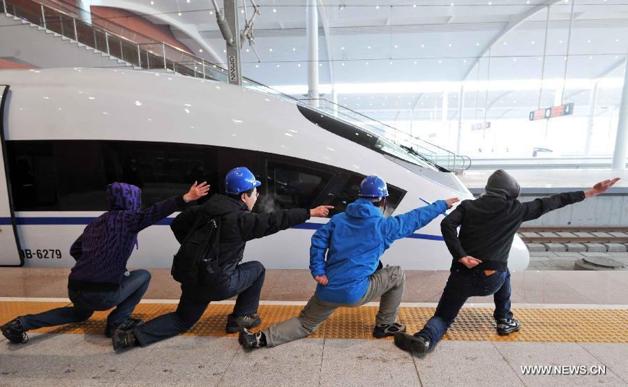 Passengers imitate the hand signals of flight deck crew of aircraft carrier beside a high-speed train at the Harbin West Railway Station in Harbin, capital of northeast China's Heilongjiang Province, Dec. 1, 2012. (Xinhua/Wang Jianwei)