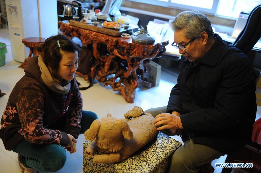Renowned sculptor Zhou Guozhen (R) comments on a piece of work created by his daughter Zhou Hua in Jingdezhen, east China's Jiangxi Province, Dec. 1, 2012. (Xinhua/Li Xinhua)