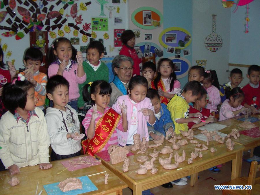 Renowned sculptor Zhou Guozhen (C) gives sculpture lesson to children of a local kindergarten in Jingdezhen, east China's Jiangxi Province, Nov. 17, 2011. (Xinhua)