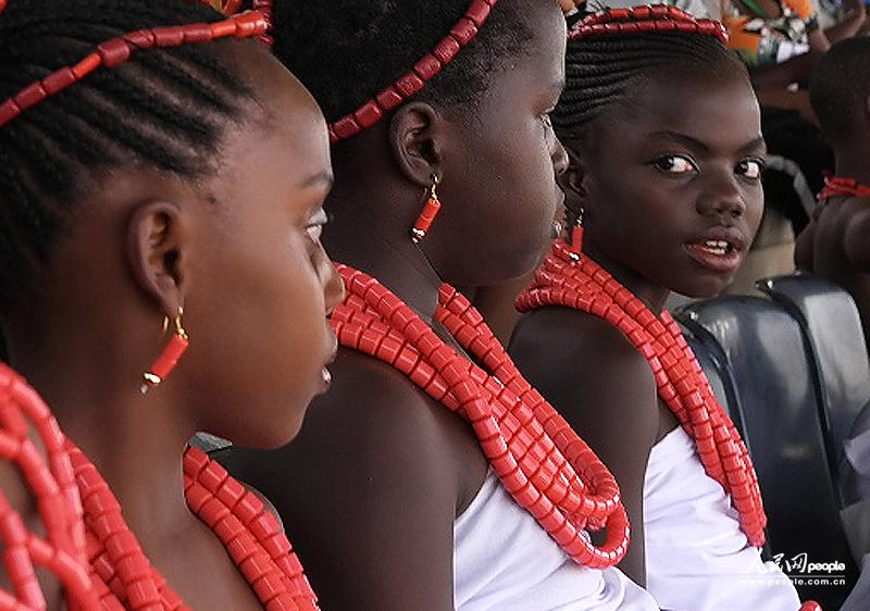 Girls wearing red necklaces earrings and hair bands sit in rows.(People's Daily Online/ Li Liang)