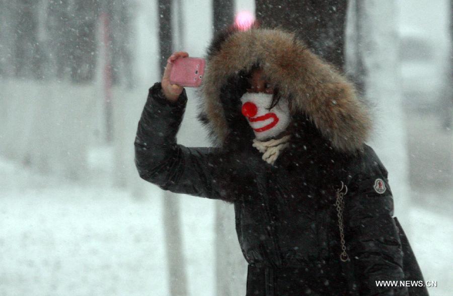 A woman takes photos amid snowstorm at a street in Shenyang, capital of northeast China's Liaoning Province, Dec. 3, 2012. Snow fell in most parts of the northeast of China, and local area had a blizzard. Liaoning Province issued a continuous blizzard warning signal from early Monday morning, while issuing the first alert for the blizzard at Shenyang and other areas. (Xinhua) 