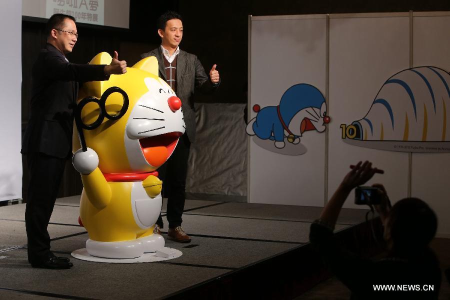 Guests are invited to pose for a photo with a character of Doraemon manga series during a press conference of an exhibition with the theme "100 years before the birth of Doraemon" in Taipei, southeast China's Taiwan, Dec. 3, 2012. (Xinhua/Xing Guangli) 