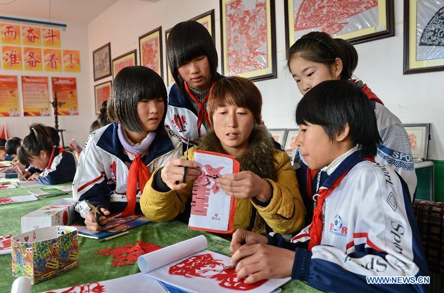 A paper-cut teacher demonstrates paper cut for students at Hope Elementary School in Longwangmiao Township of Qinglong Man Autonomous County, north China's Hebei Province, Dec. 2, 2012. The school invited paper-cut artists to teach students the traditional Chinese paper cut art. (Xinhua/Yang Shiyao)