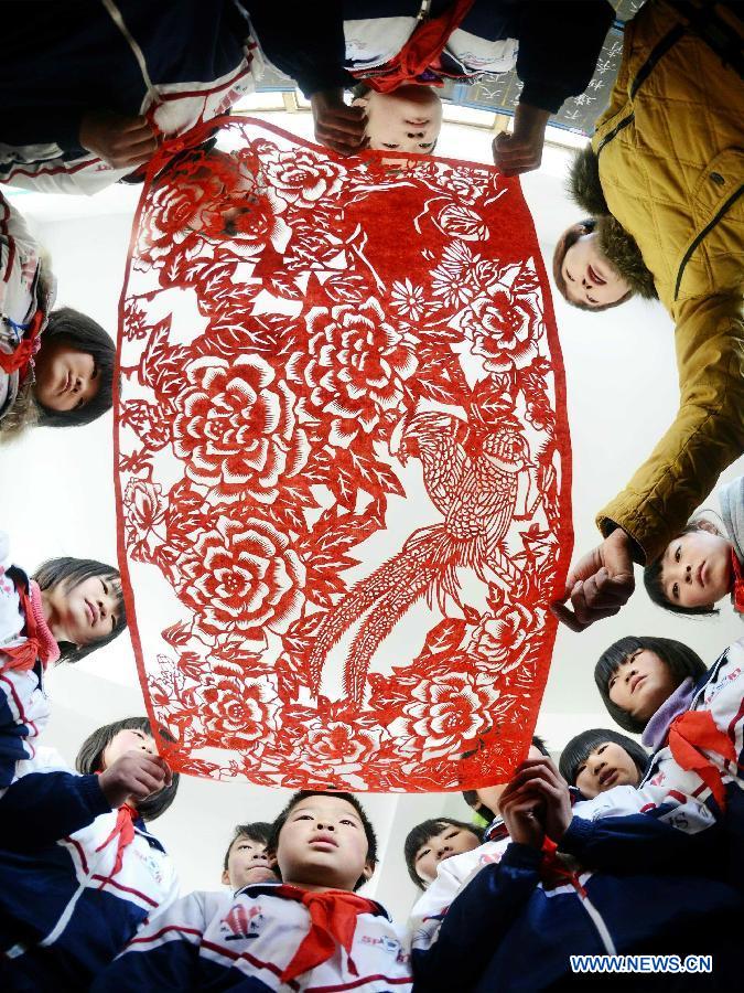 Students gather to watch a Chinese paper-cut work at Hope Elementary School in Longwangmiao Township of Qinglong Man Autonomous County, north China's Hebei Province, Dec. 2, 2012. The school invited paper-cut artists to teach students the traditional Chinese paper cut art. (Xinhua/Yang Shiyao)