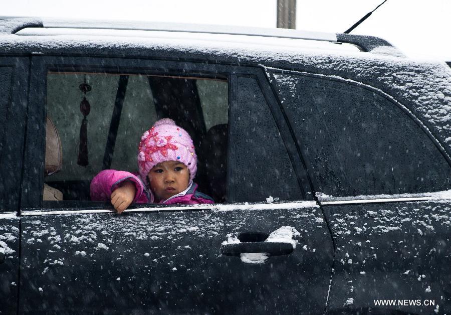 A girl looks through a car window during a snowfall in Urumqi, capital of northwest China's Xinjiang Uygur Autonomous Region, Dec. 3, 2012. The city witnessed a snowfall on Monday, where the temperature fell to approximately 14 degrees Celsius below zero. (Xinhua/Wang Fei)