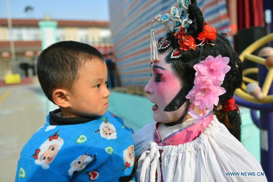 Miao Xueyan, performer from Xihuangcun Amateur Drama Group, holds her son during the break of a show in Xihuang Village of Zouping County, east China's Shandong Province, Nov. 24, 2012. (Xinhua/Zhu Zheng)