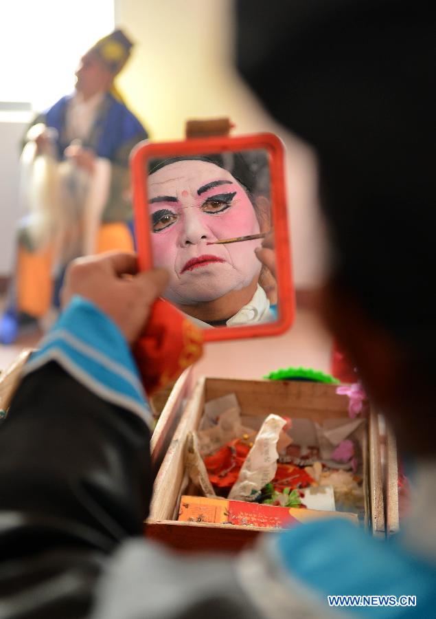 A performer from Xihuangcun Amateur Drama Group puts on make up in a dressing room in Xihuang Village of Zouping County, east China's Shandong Province, Nov. 24, 2012. (Xinhua/Zhu Zheng)