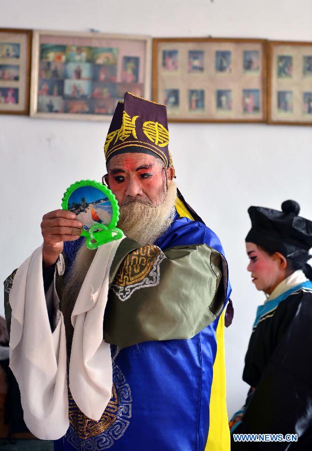 A performer from Xihuangcun Amateur Drama Group named Liu Qinghe puts on make up in a dressing room in Xihuang Village of Zouping County, east China's Shandong Province, Nov. 24, 2012. (Xinhua/Zhu Zheng)