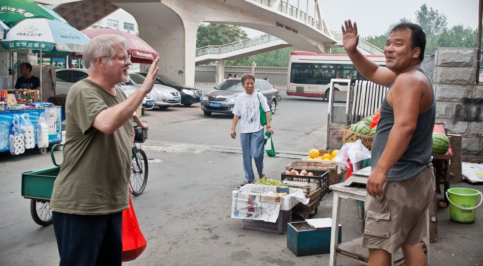 Richard Sears (L) bids farewell to a watermelon seller in Tianjin, north China, Aug. 8, 2012.(Xinhua Photo)